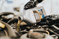Close-up of a mechanic pouring engine oil into a car engine, highlighting maintenance work.
